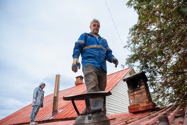 Two-man crew walking a roof between chimneys